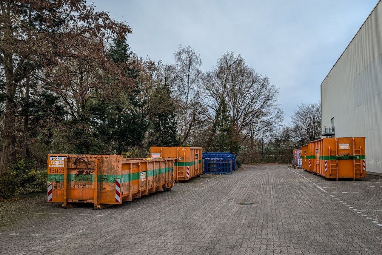 Outdoor view of industrial waste bins lined up beside a warehouse in winter.